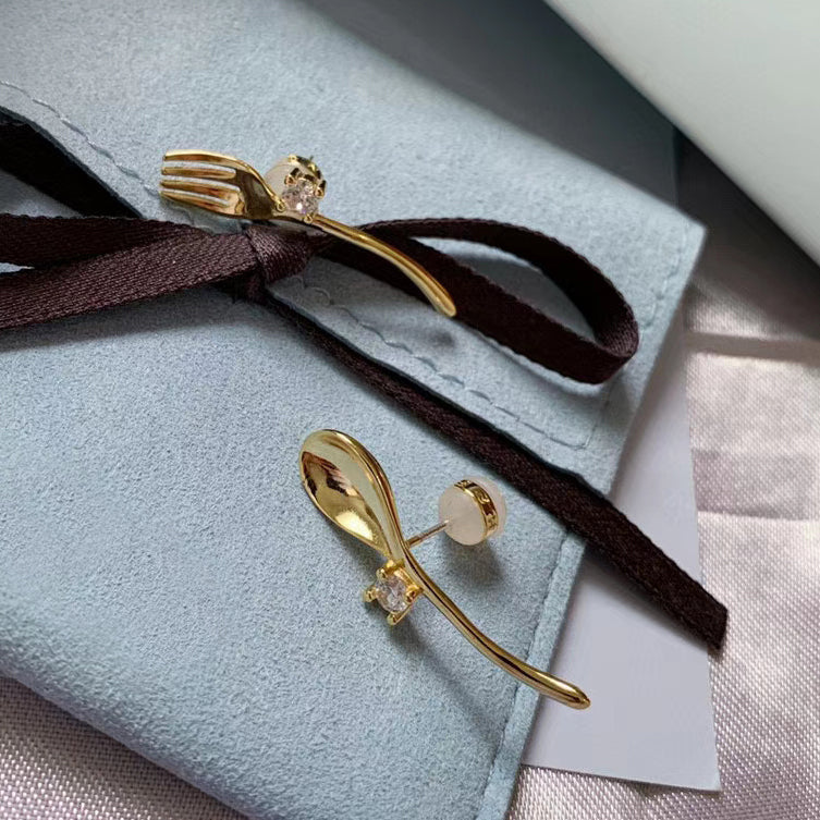 Golden cutlery and diamond earrings